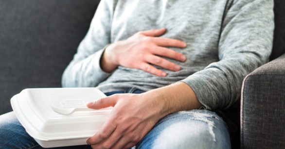 man feeling sick holding plastic container
