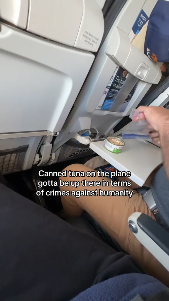 A man eating tuna on an airplane