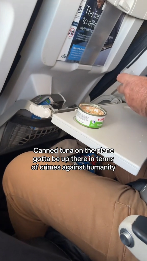 A man eating tuna on an airplane