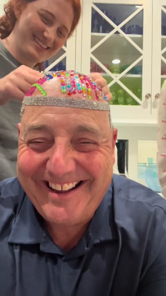 Two daughters bedazzling their dad's bald head