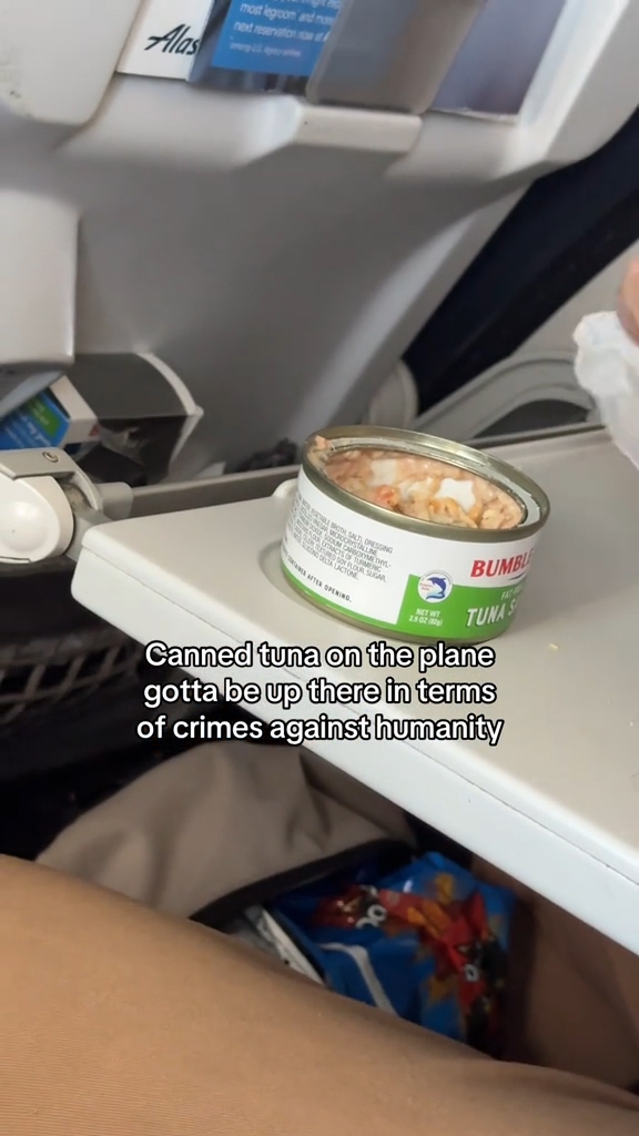 A man eating tuna on an airplane