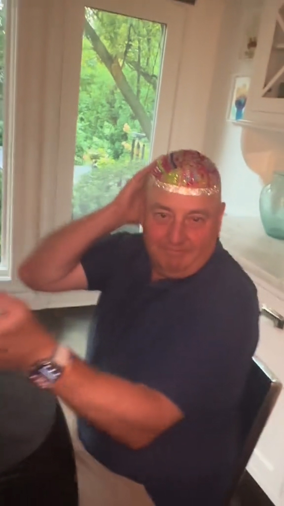 Two daughters bedazzling their dad's bald head