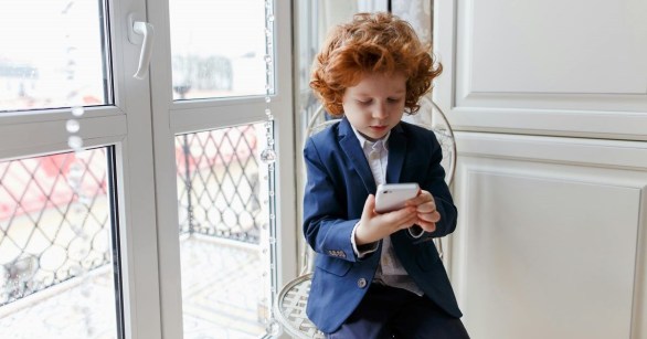 A child in a suit on his phone