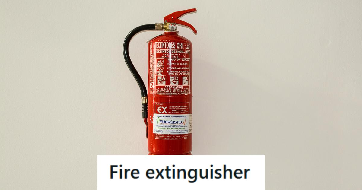 Red fire extinguisher hanging against a tan wall
