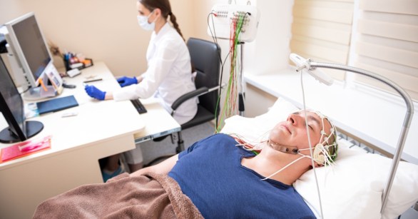 Man taking sleep test with doctor in background