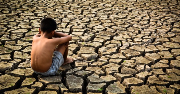 little boy sitting on dry ground
