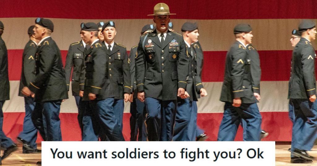 Army soldiers walking across a stage in front of a giant flag