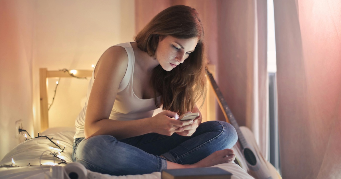 A woman using her phone on her bed