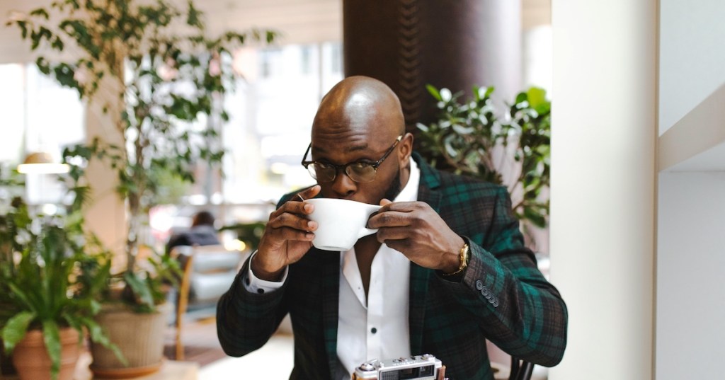 A bald man sipping a coffee