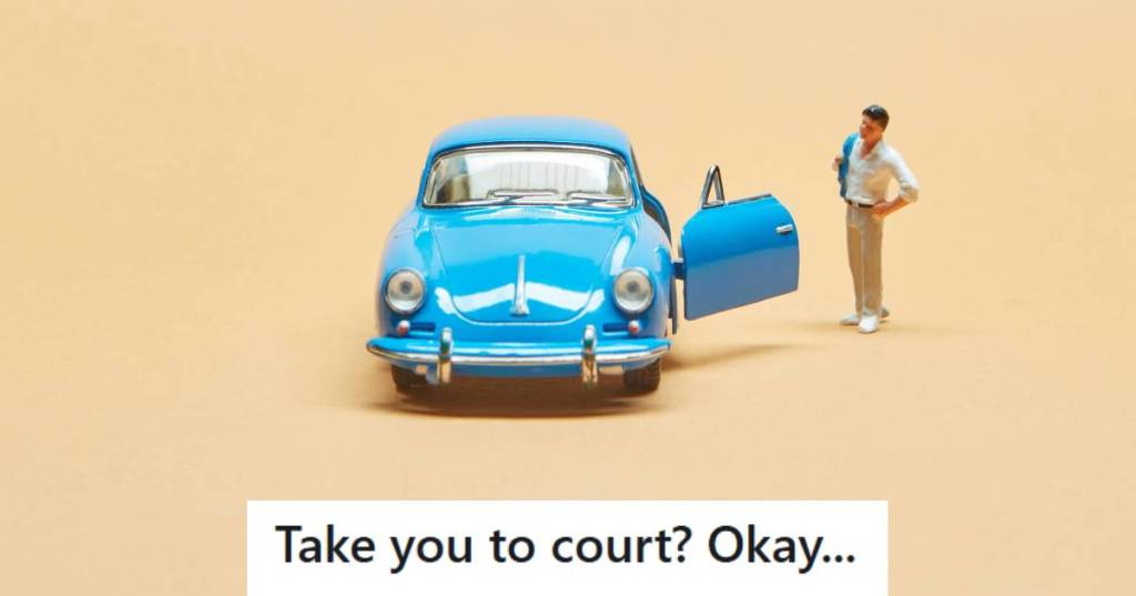 Toy man standing outside of a small blue car looking at damage