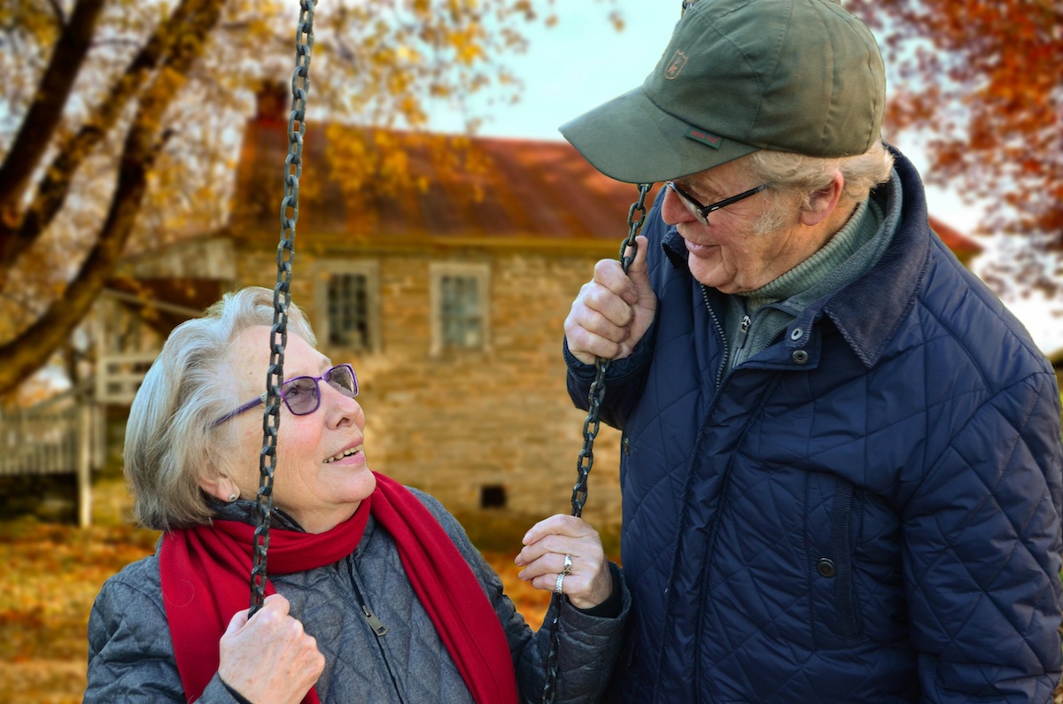An elderly couple using a swing set in the fall 