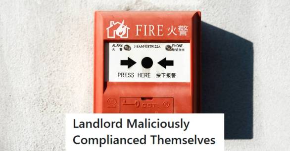 Red fire alarm in the sunlight against a whitish-gray wall