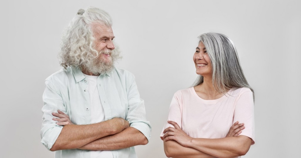 two older people with grey hair smiling at each other