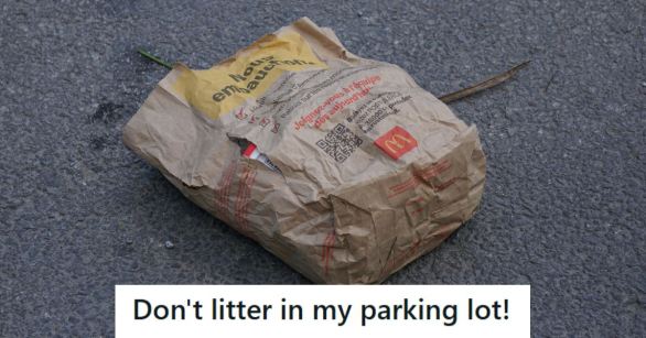 Bag of fast food trash laying in the middle of a parking lot