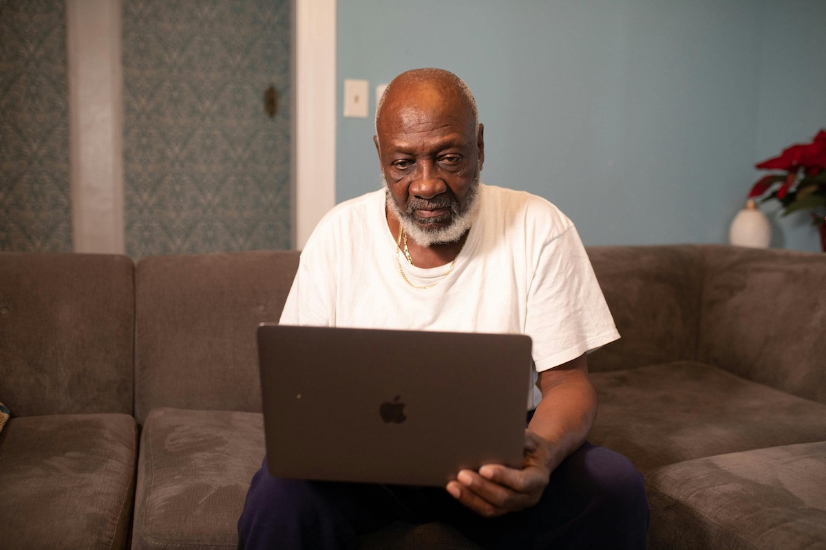 An older man on a couch using a macbook