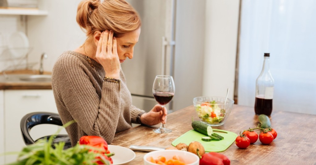 Woman with headache drinking red wine