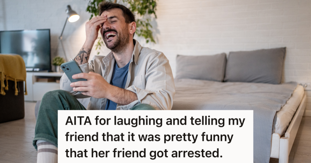 man sitting on the floor laughing while looking at his phone