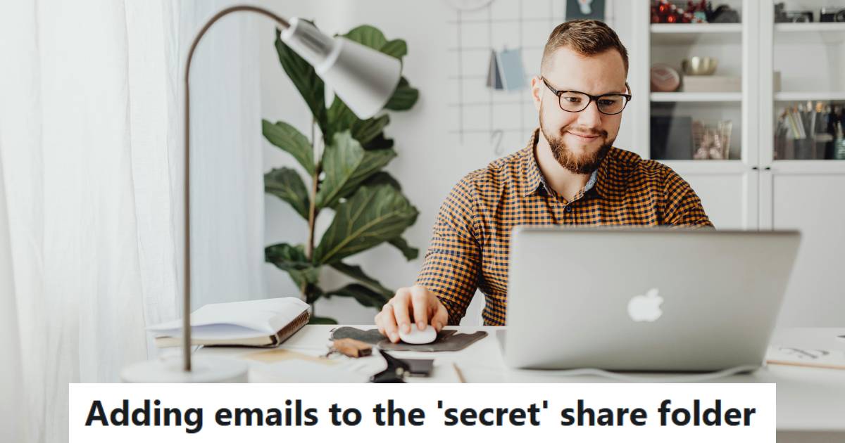Man smiling as he adds more complete emails to a shared folder at work.