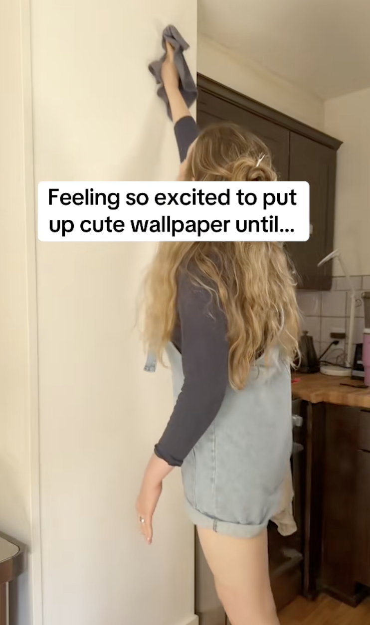 woman putting up wallpaper