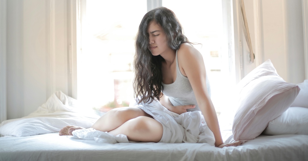 A woman in bed with a stomach ache