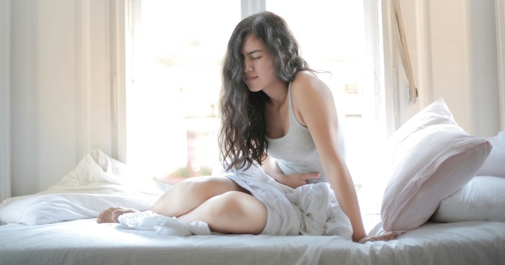 A woman in bed with a stomach ache