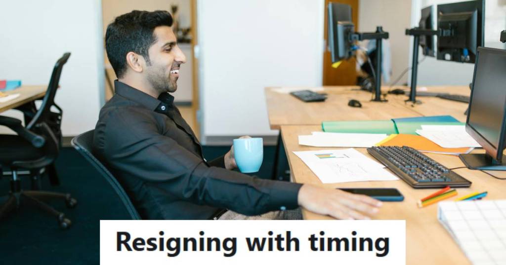 Man sitting at his desk smiling, because he resigned the right way, not how his manager wanted