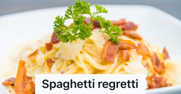 A bowl of carbonara pasta with bacon bits and parsley leaves