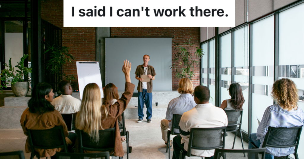 Man standing in front of seated group next to a window.