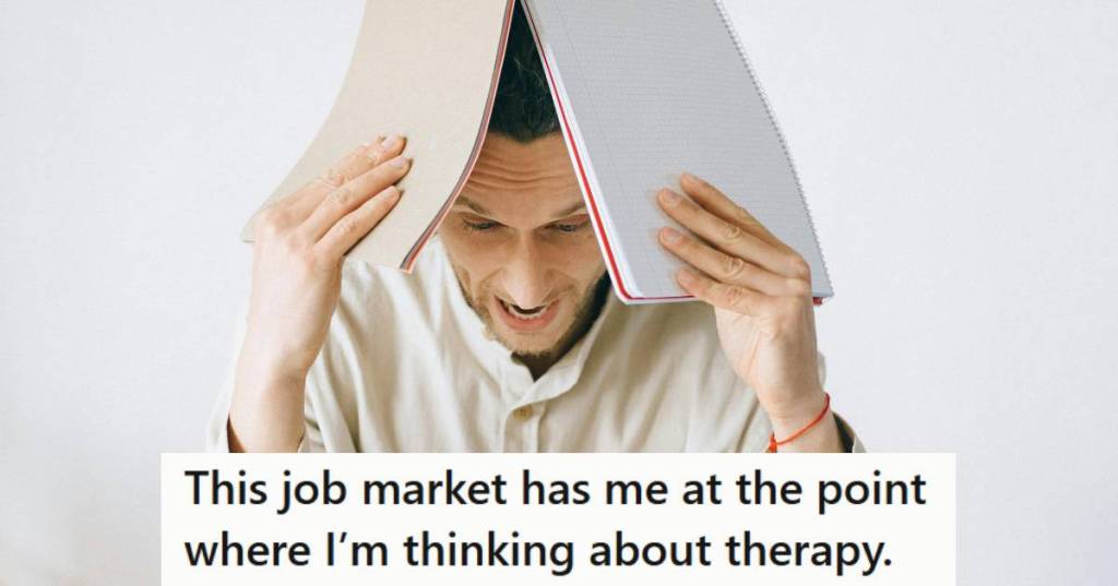 Man sitting at a table stressed with a book over his head