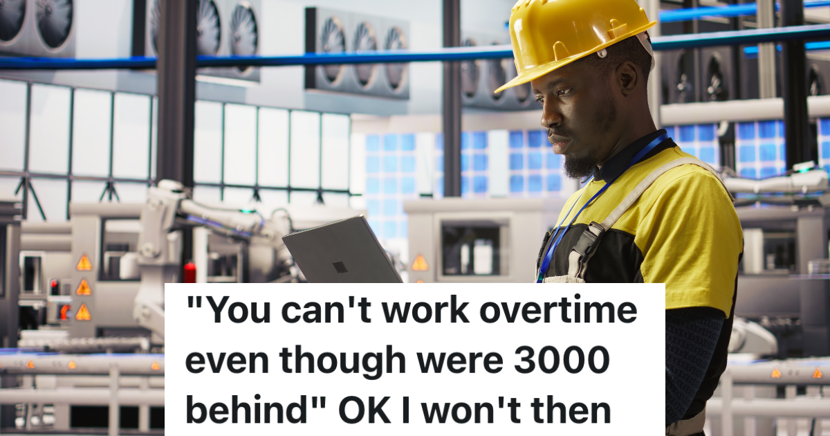 man in a factory wearing a hardhat and looking at a laptop
