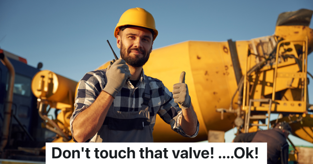 man in hardhat giving a thumbs up single in front of a concrete mixer