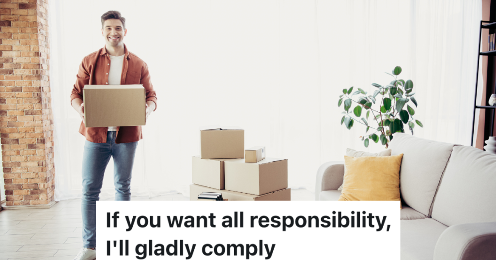 smiling man holding a moving box with more boxes stacked on the floor