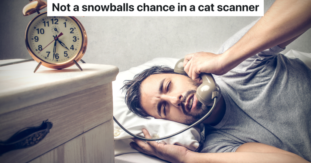 man answering a landline phone while still in bed