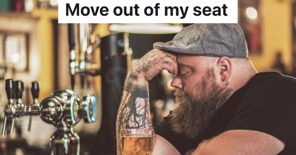 man in a hat and black t-shirt sitting in a pub