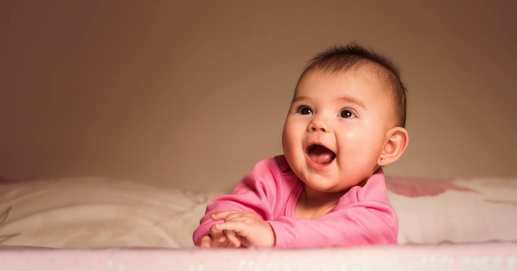 A baby laughing on a blanket