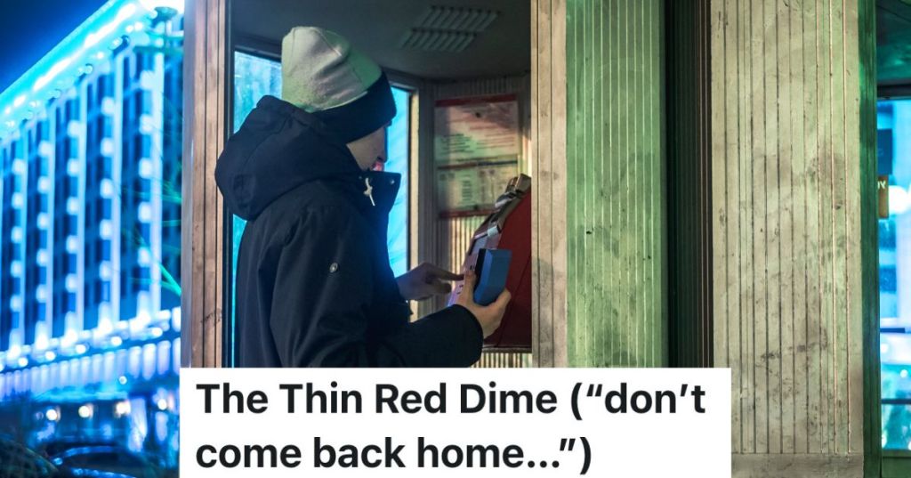 young man using pay phone at night