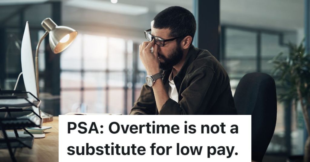 man rubbing his eyes while sitting at a desk