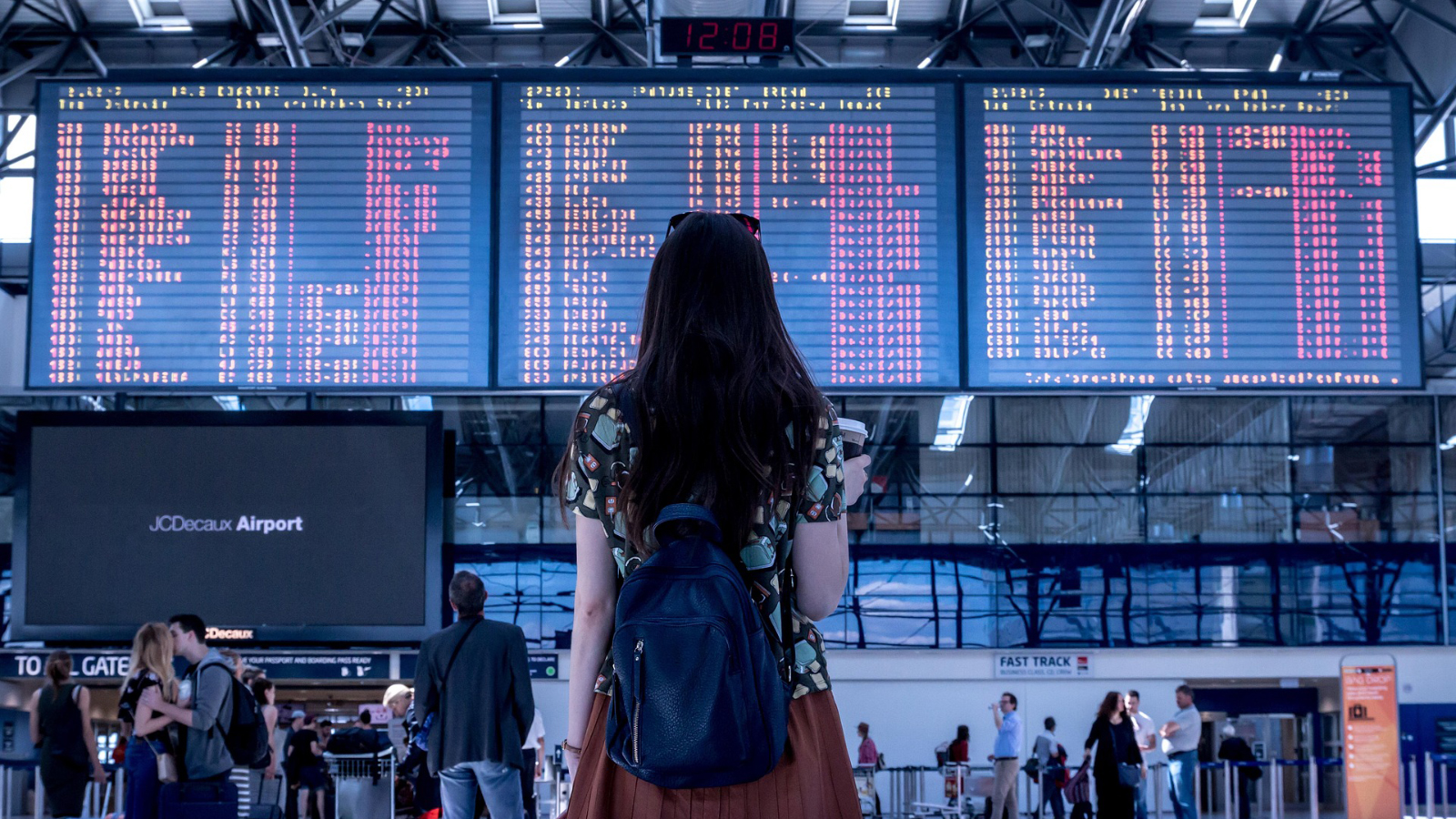 A traveler looking up at a giant airport board