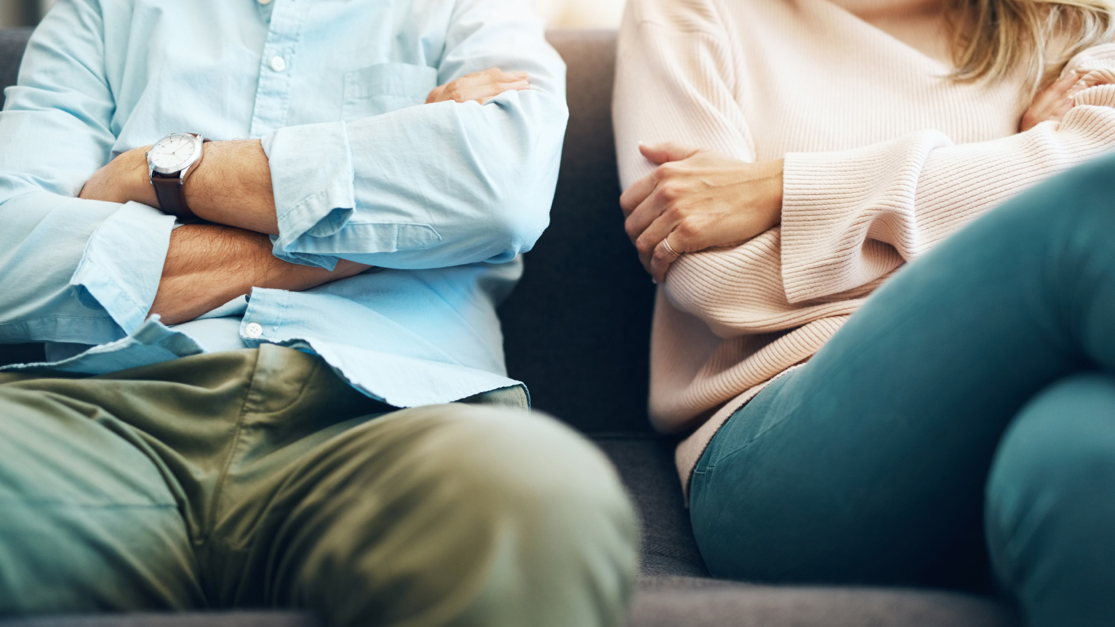 A couple on a couch with arms folded in anger
