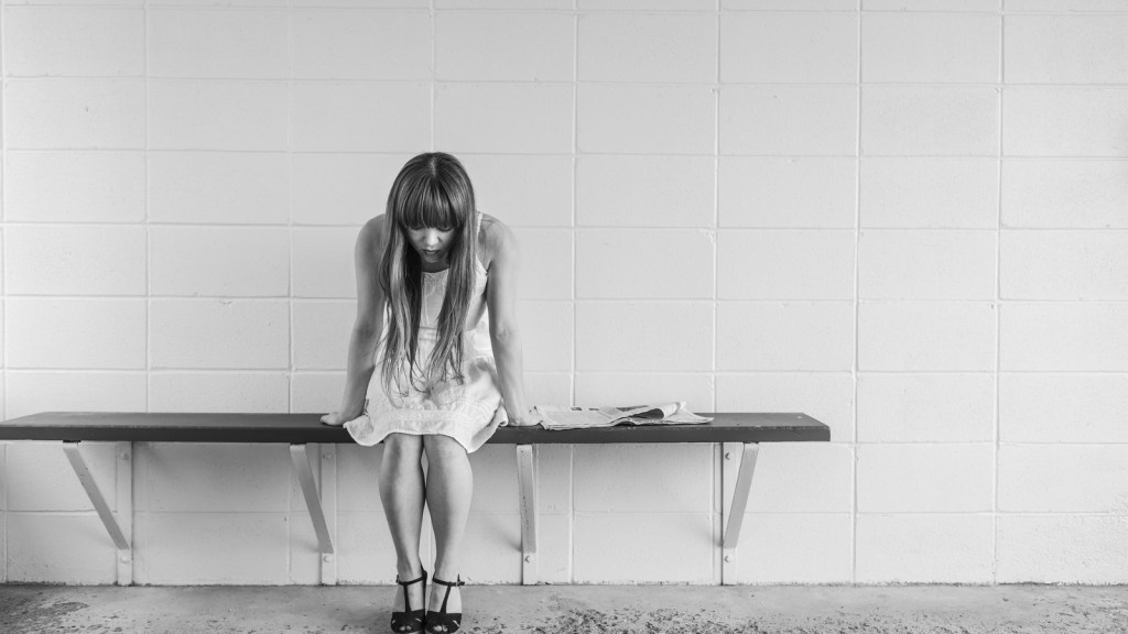 A woman looking upset sitting on a bench