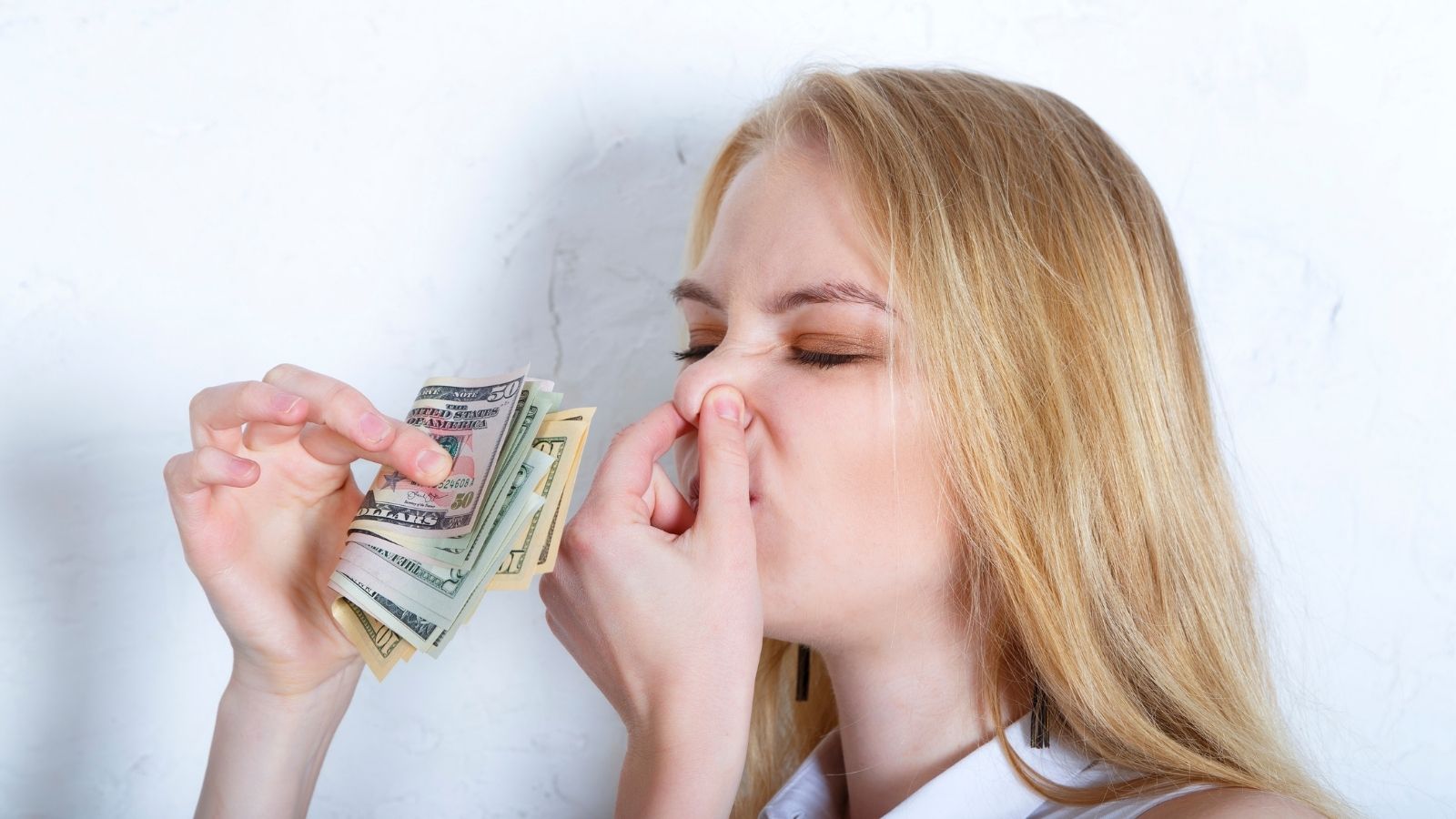 woman holding her nose and cash
