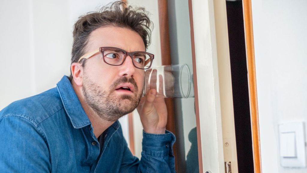 man listening with glass at the door