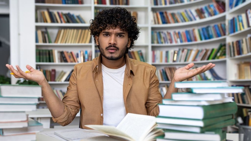 frustrated college student in front of bookcase