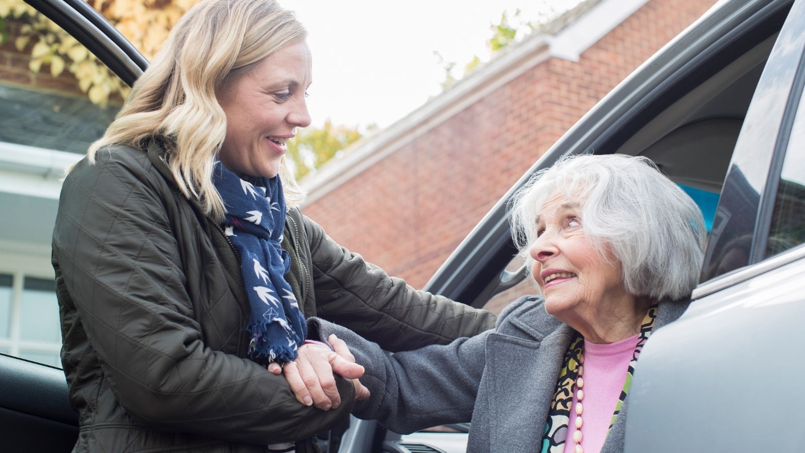 woman helping elderly woman into car
