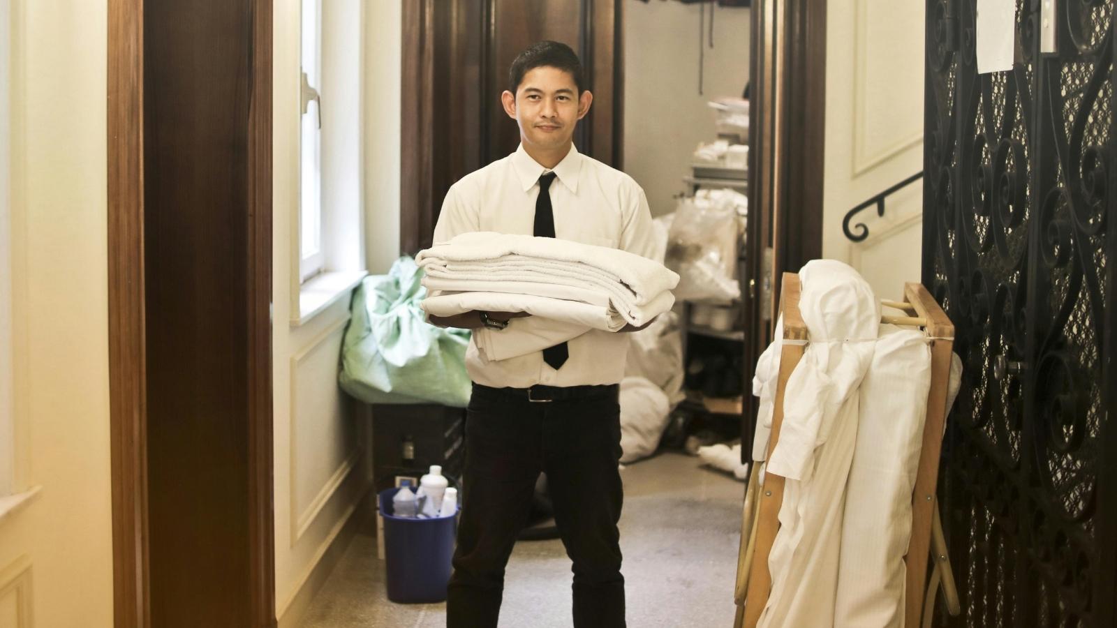 hotel employee holding a stack of towels