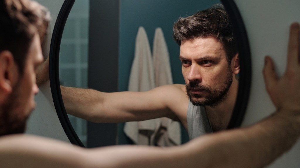 A pensive man looking in a mirror