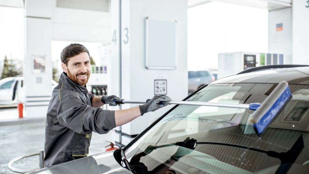 man washing car window at gas station