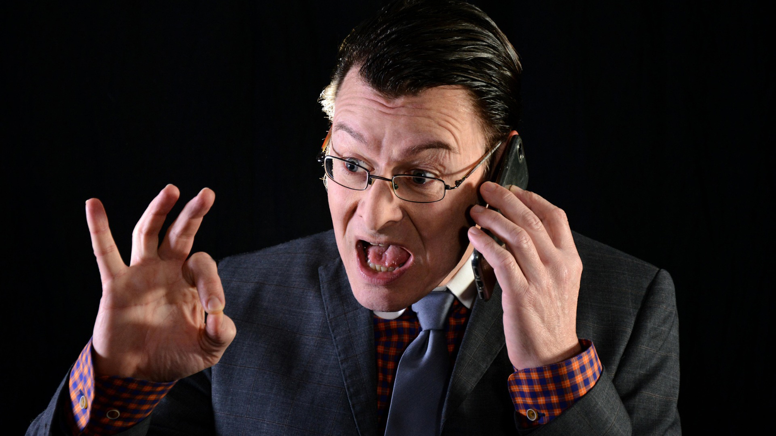 A man in a suit shouting into a phone