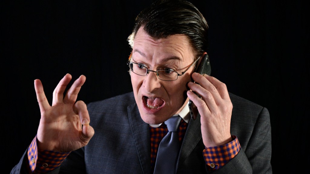 A man in a suit shouting into a phone