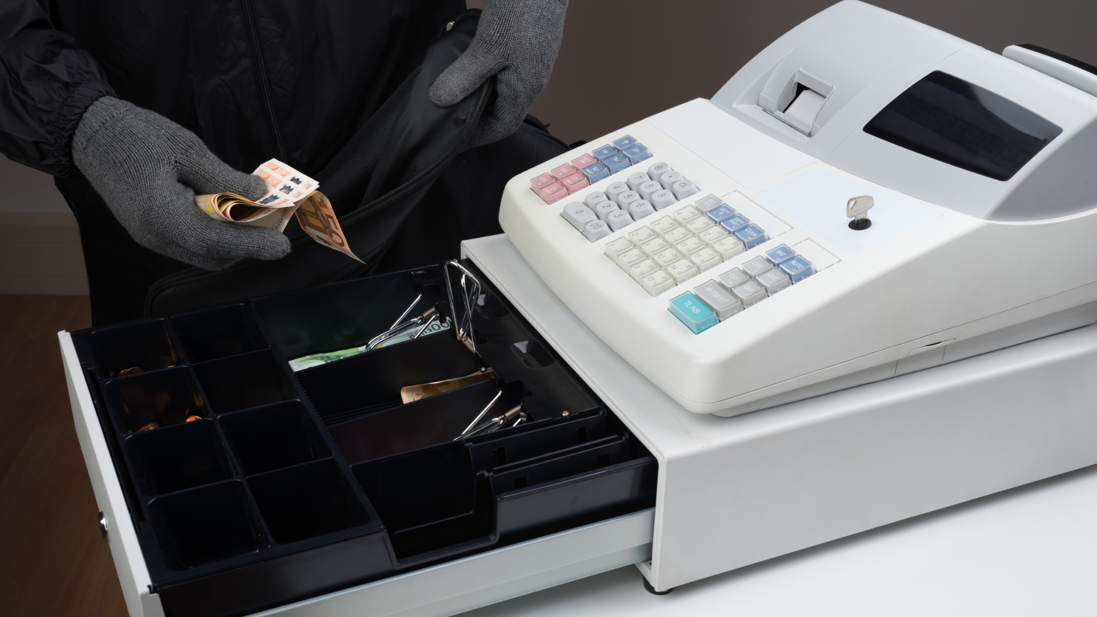 A thief taking money from a cash register